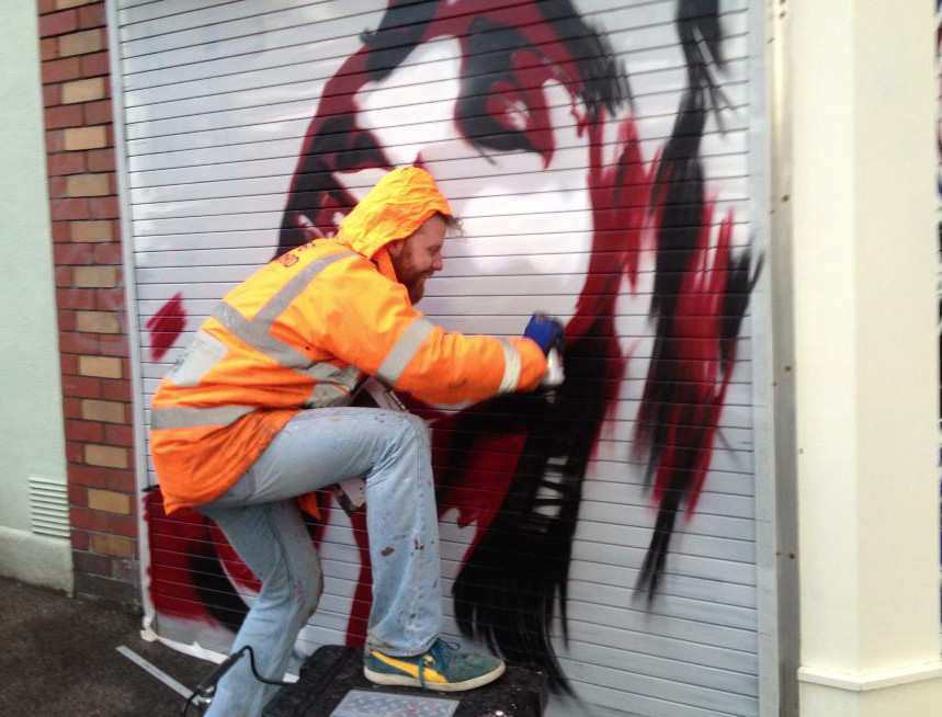 Pelmo wearing orange jacket painting on a shot shutter